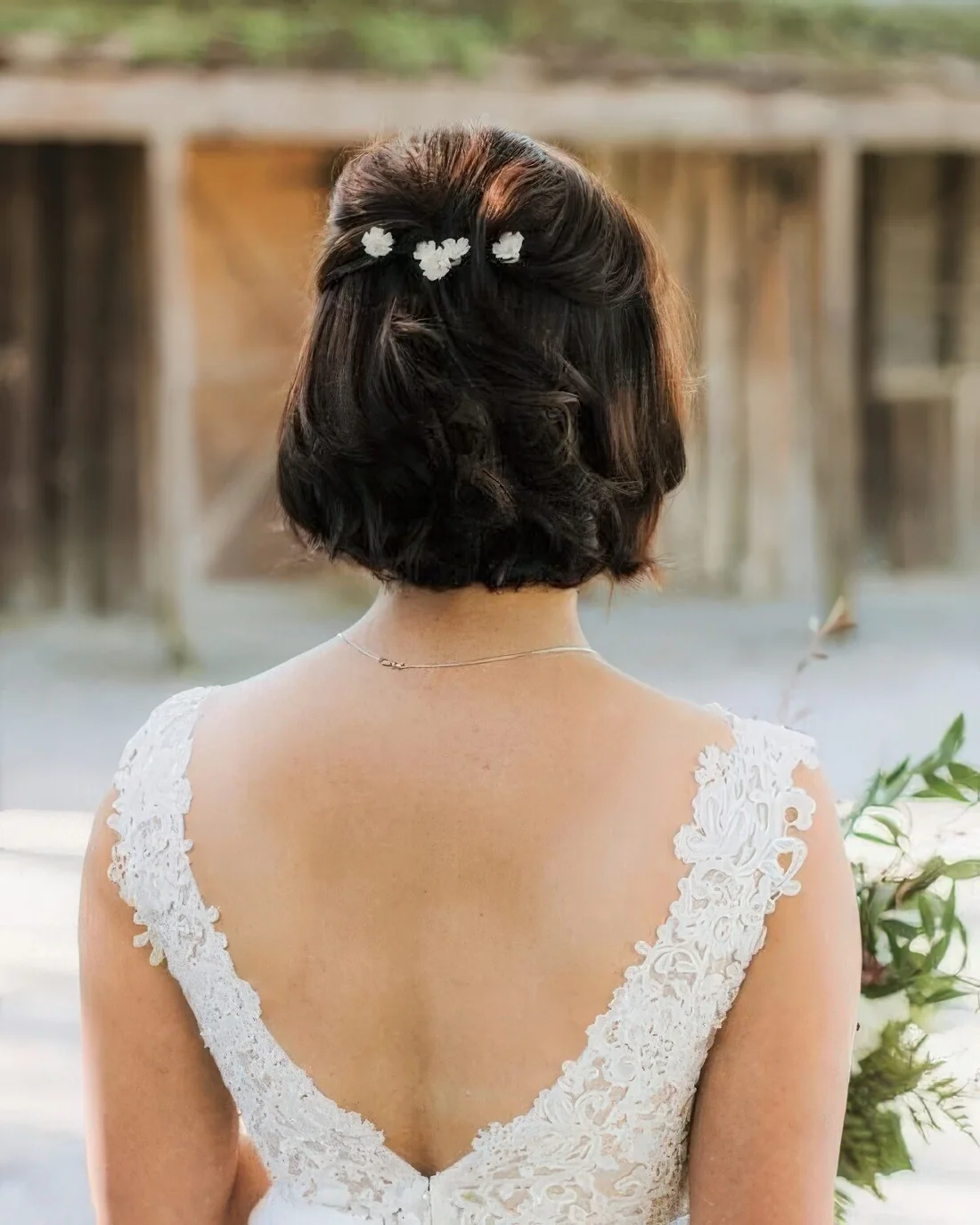 Midi bob styled as a half updo with some floral hair pins securing waves.