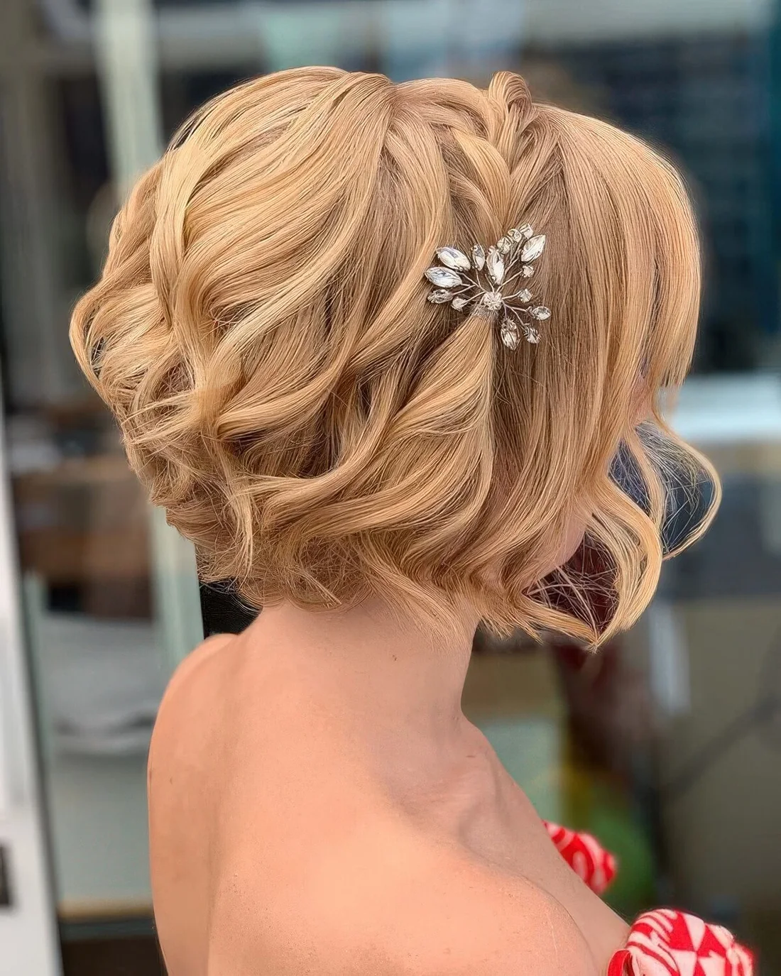 Short wavy bob accented with a braid on top the head and a single rhinestone hair piece.