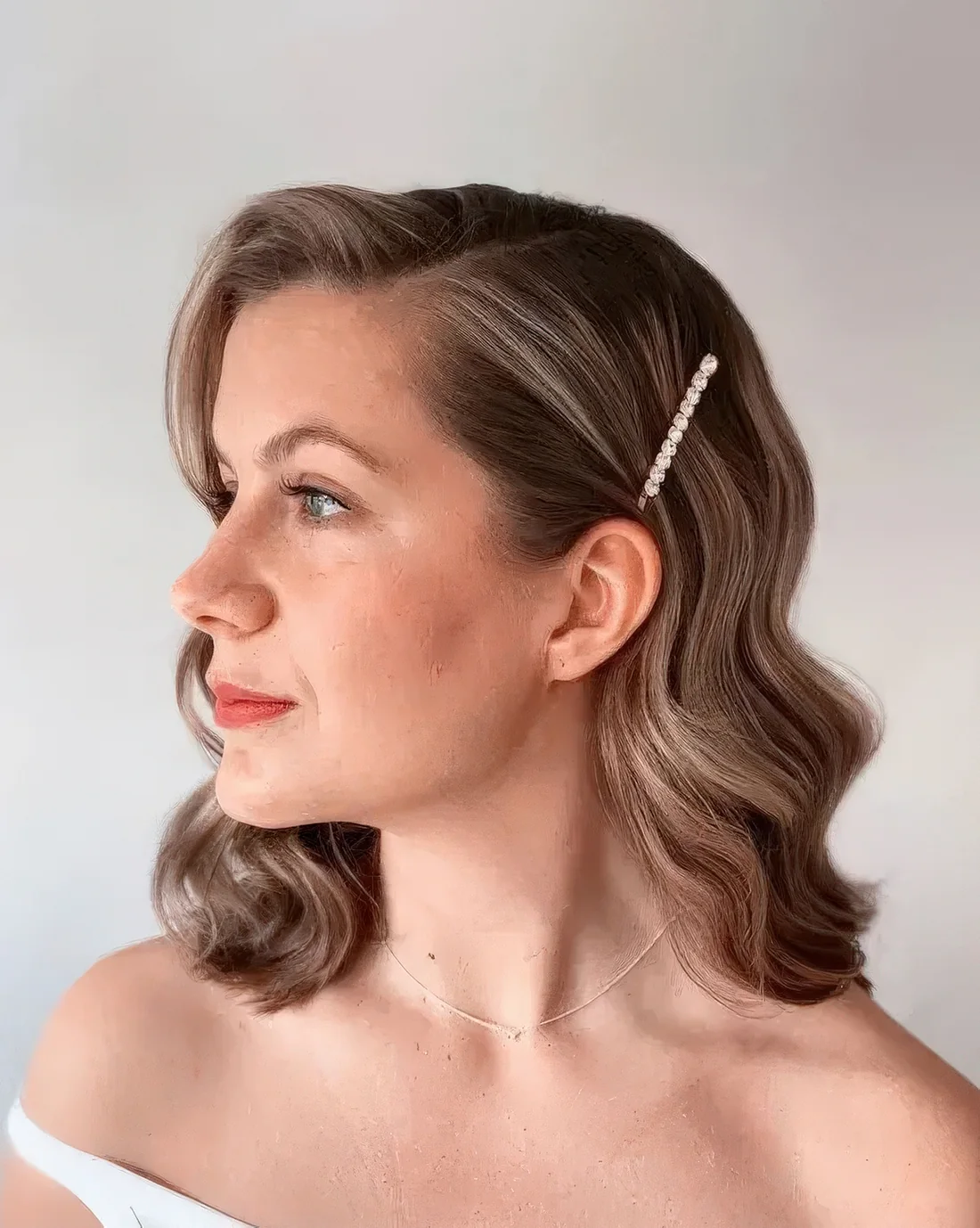 Brown wavy bob with side part and a pearl hair pin.