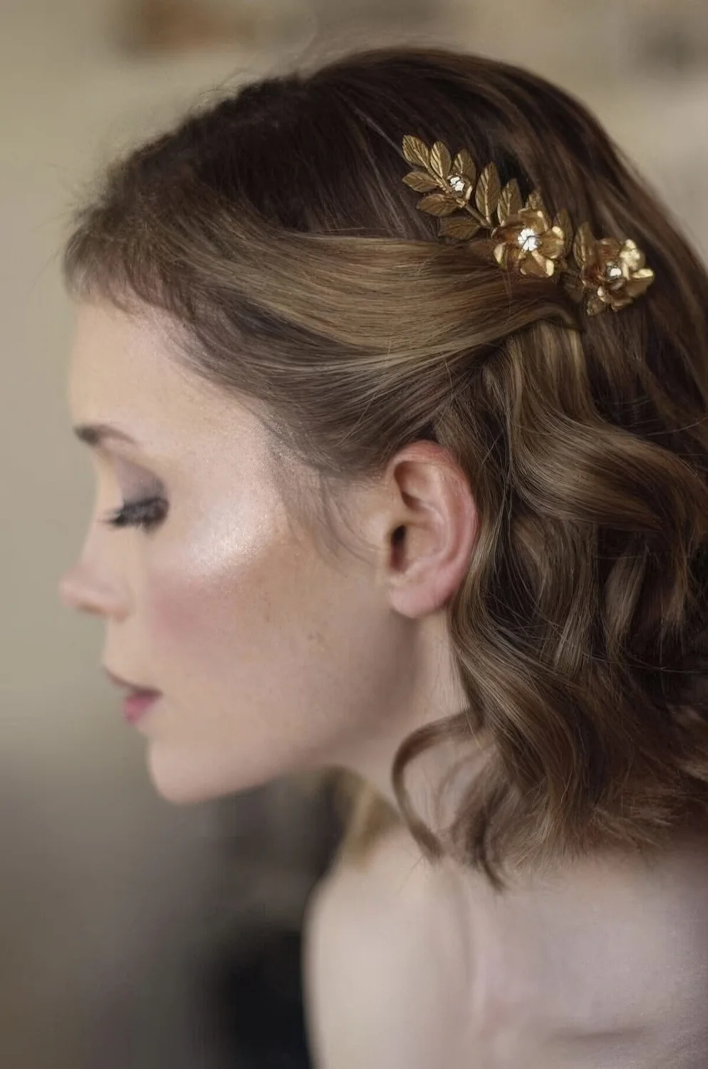 Wavy bob styled as a half updo with a little gold leaf piece.