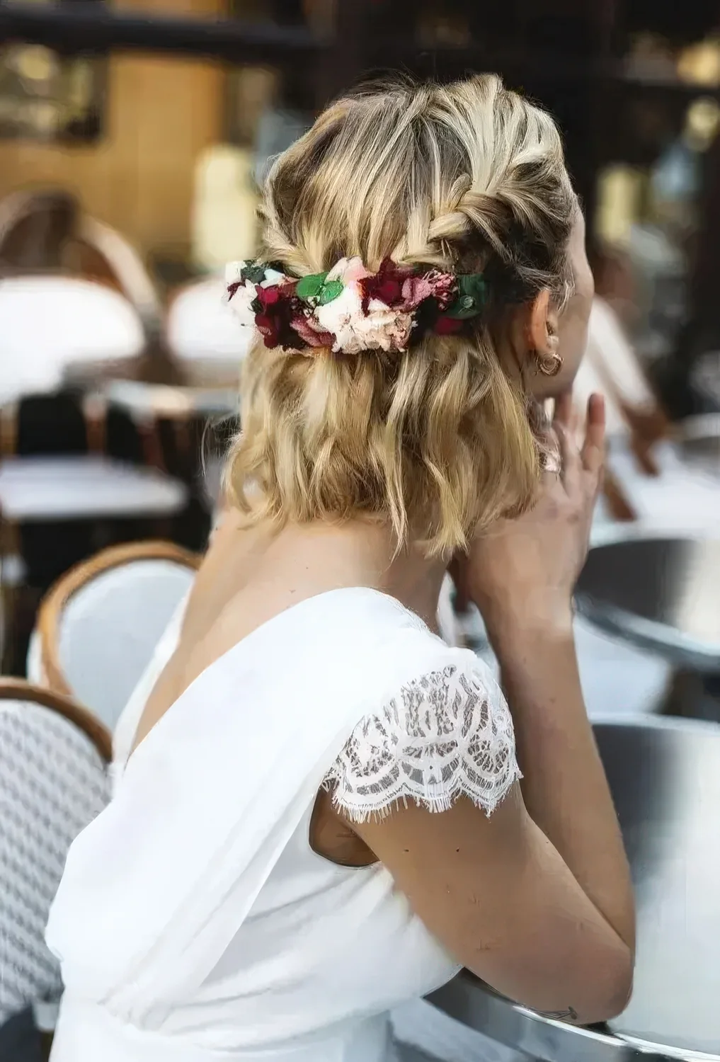 Wavy half updo with braids and a bit of blooms and greenery added to the hairstyle.