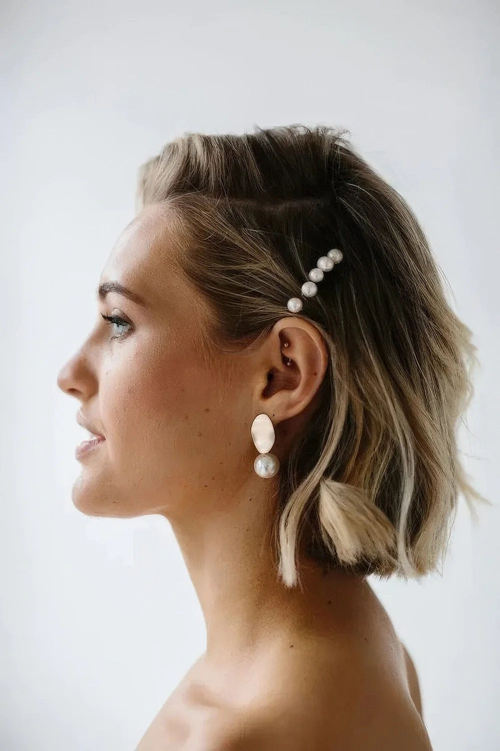 Wavy long bob with side part and a pearl hair piece plus pearl earrings are a cool modern combo.