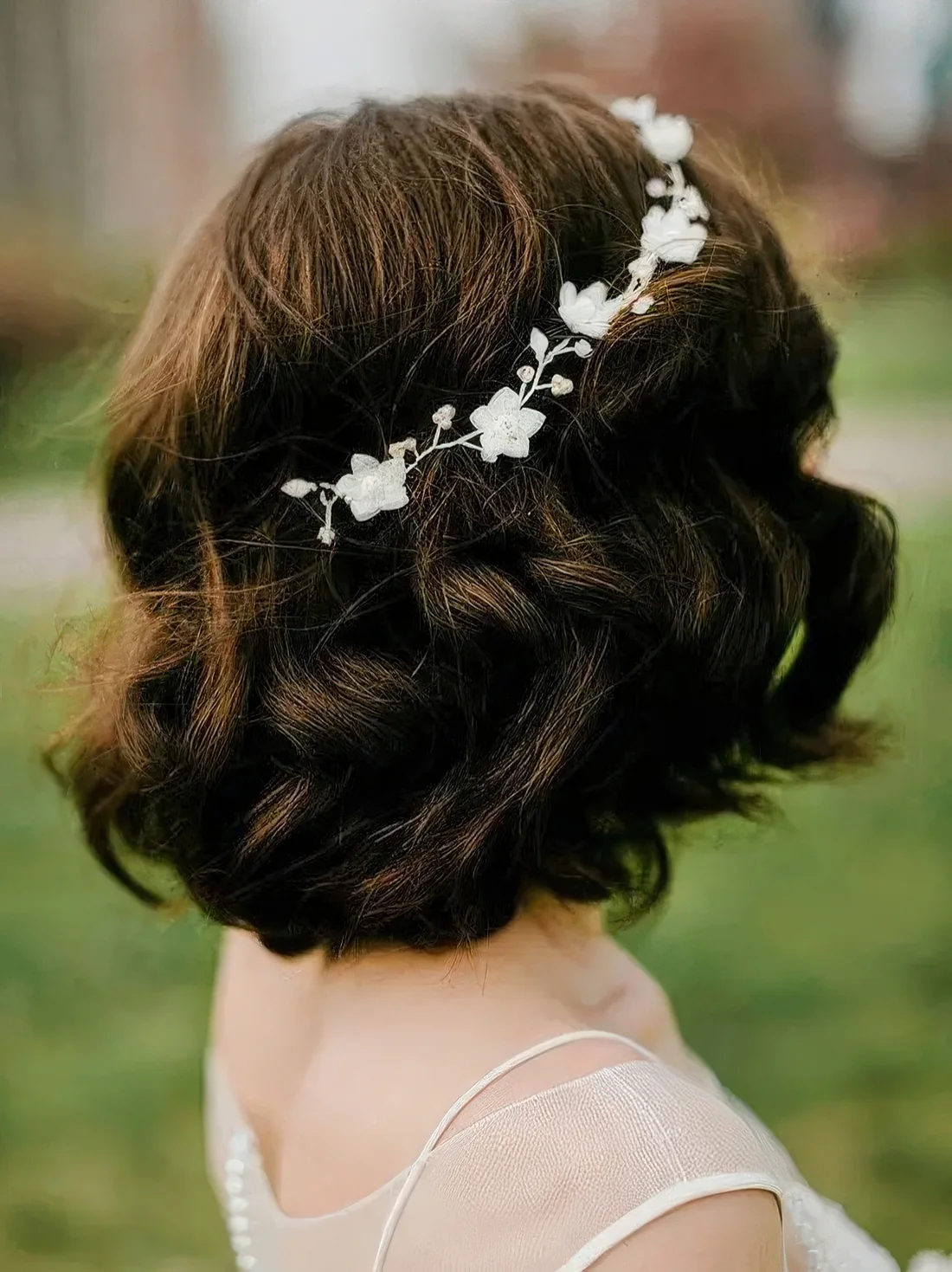Wavy long dark brown bob with a bump on top and a delicate white floral hair vine.