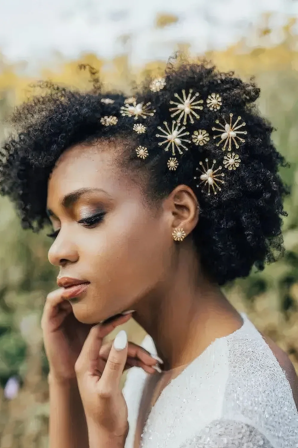 Short naturally curly hair with beautiful gold and pearl hair pins and matching earrings for a chic look.