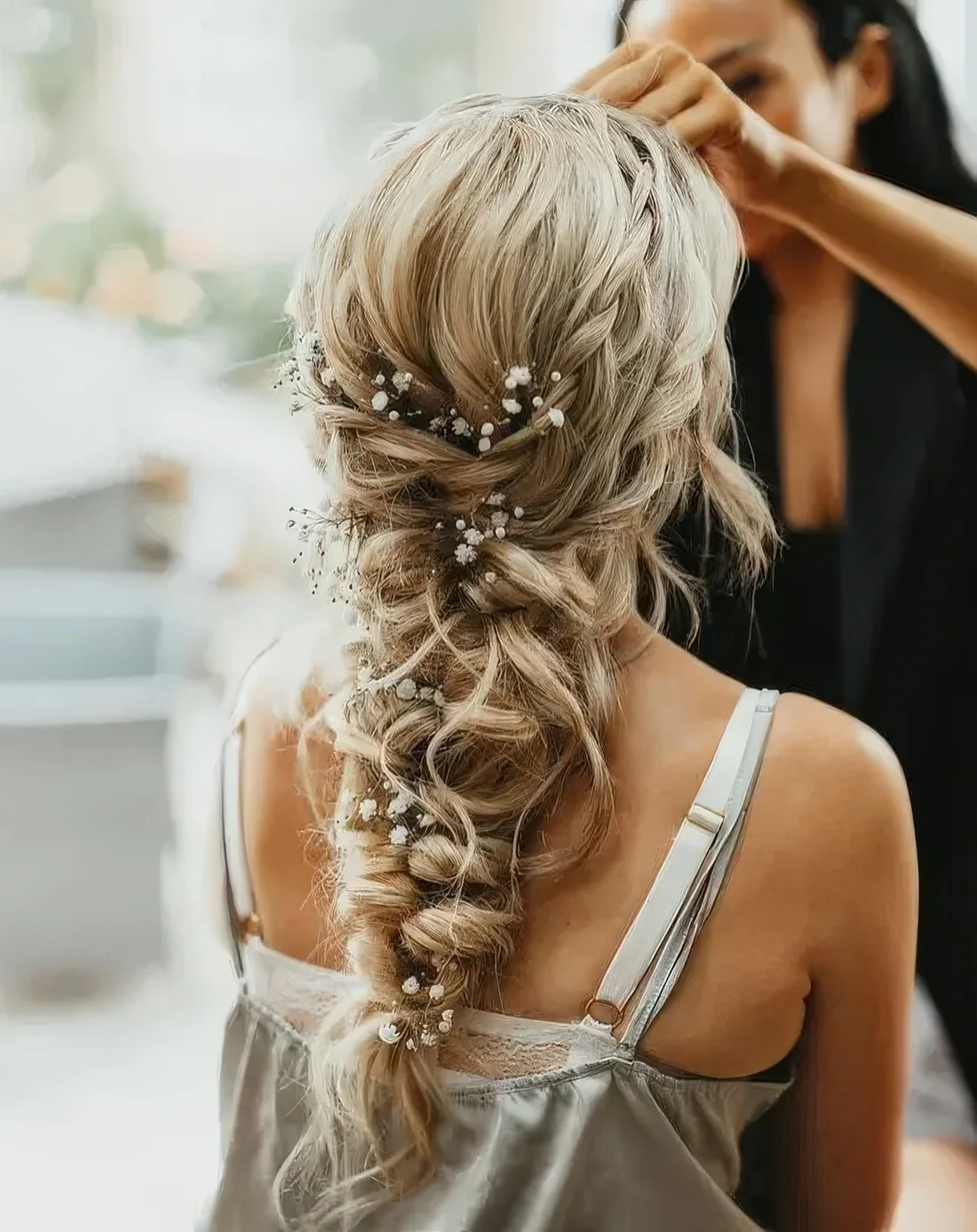 Loose and messy twisted braid with a couple of braided halos and baby's breath tucked into the braid.