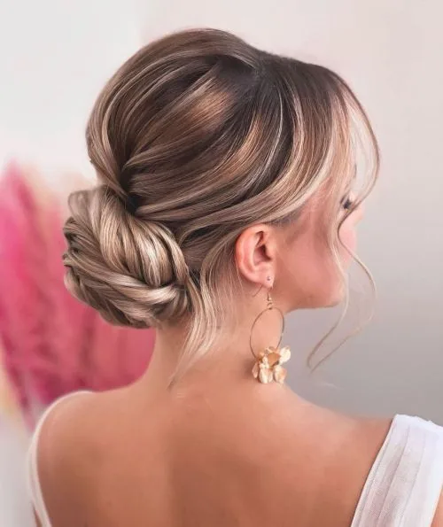 shoulder wavy blonde updo shown as a wedding guest hairstyle idea, featuring glossy finish
