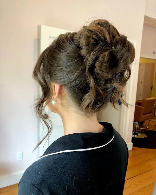shoulder wavy blonde updo shown as a wedding guest hairstyle idea, featuring volume through the crown