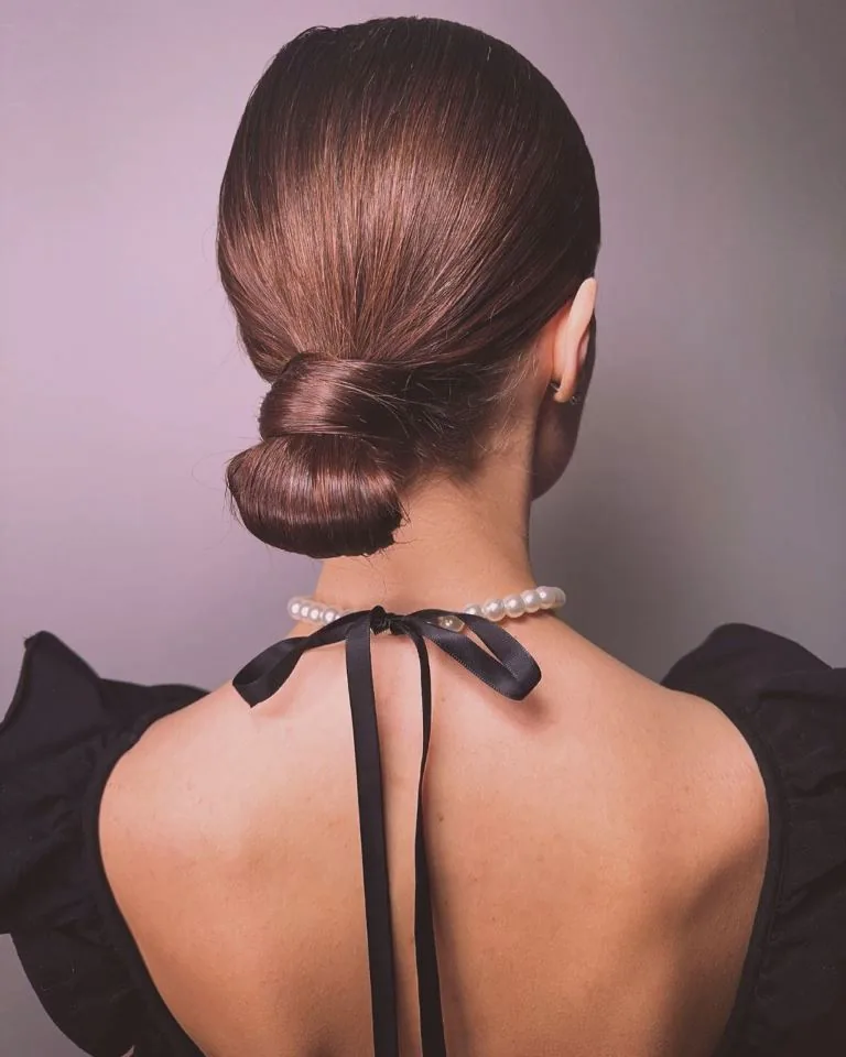 shoulder wavy blonde updo shown as a wedding guest hairstyle idea, featuring shoulder outline