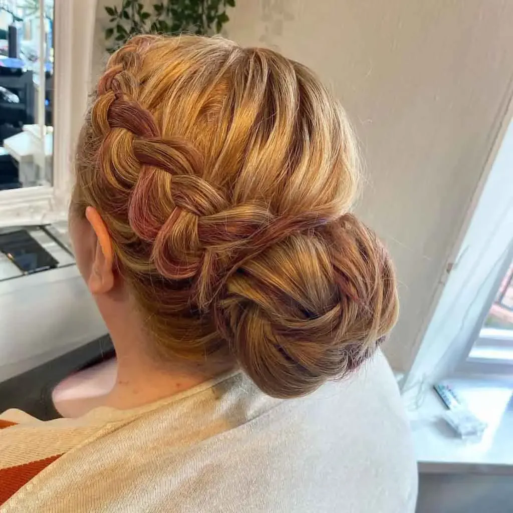 shoulder wavy blonde updo shown as a wedding guest hairstyle idea, featuring side part, shown in copper braided side bun