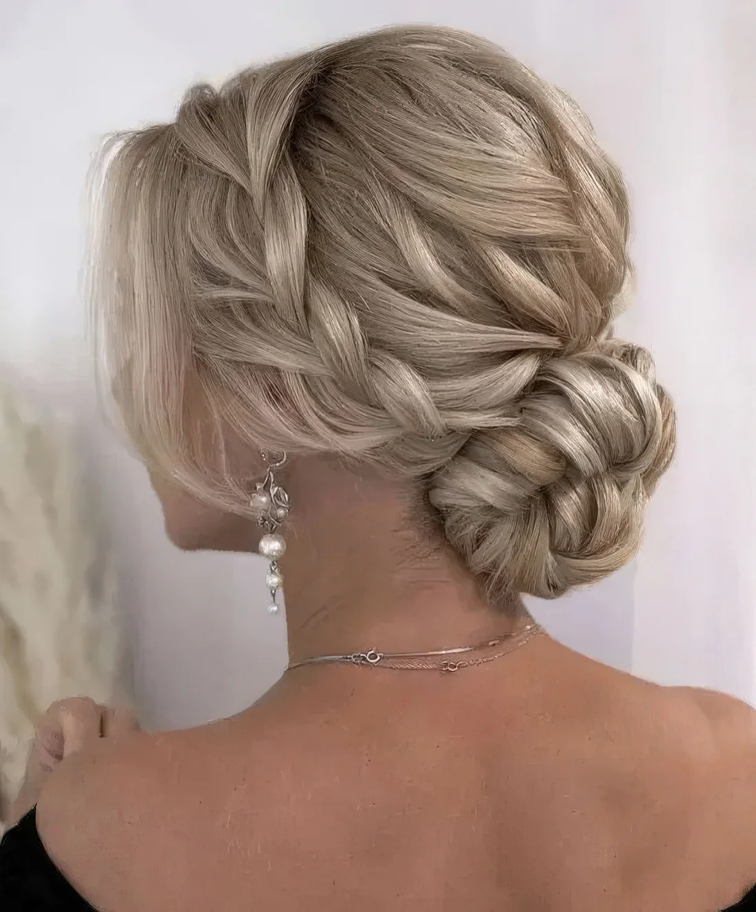 Blonde low bun with a braided halo and a braided top, face-framing locks.