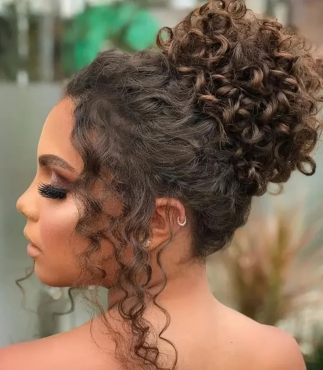 Curly top knot with some curls framing the face.