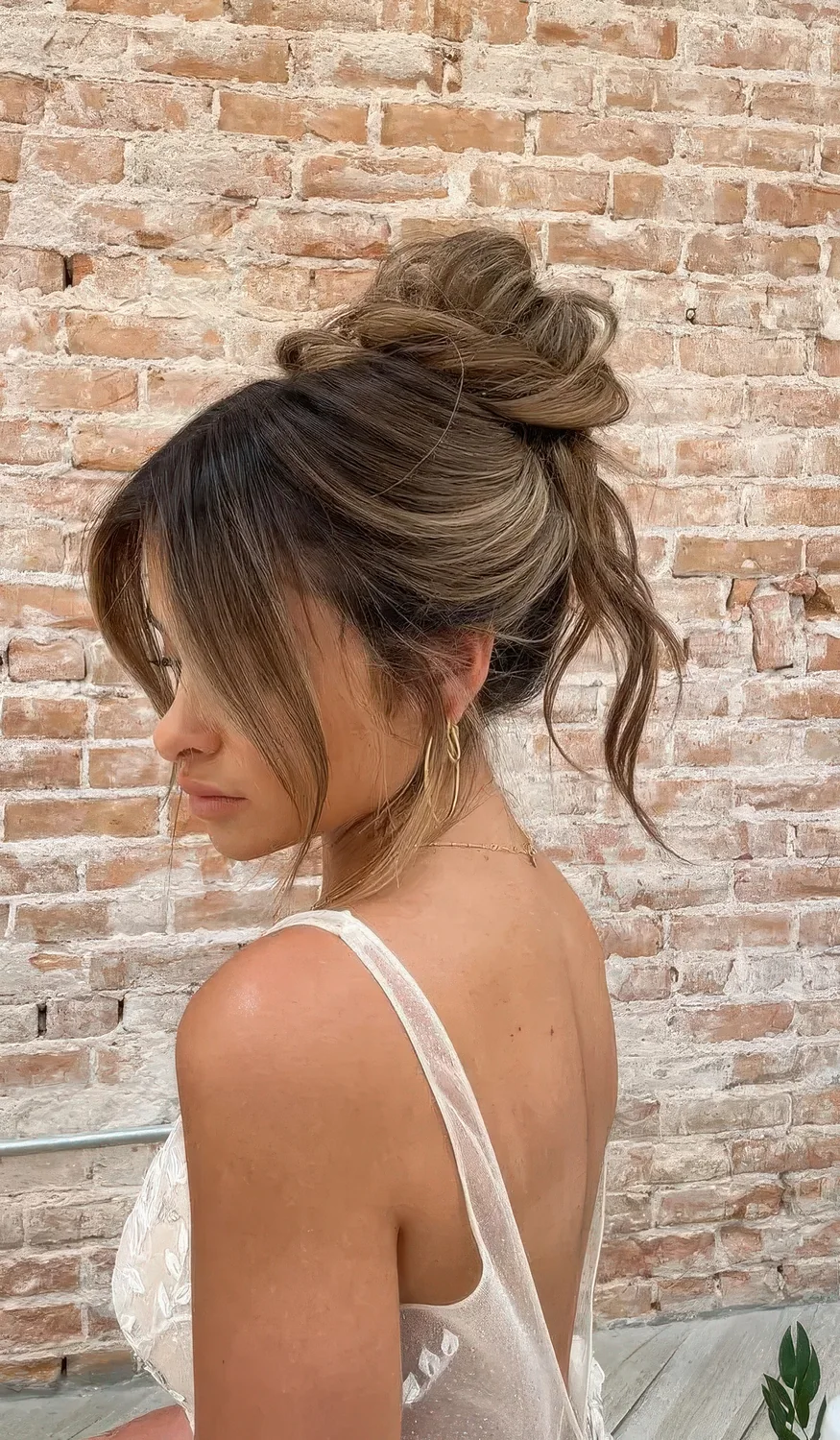 Messy twisted top knot with some hair down and face-framing bangs.