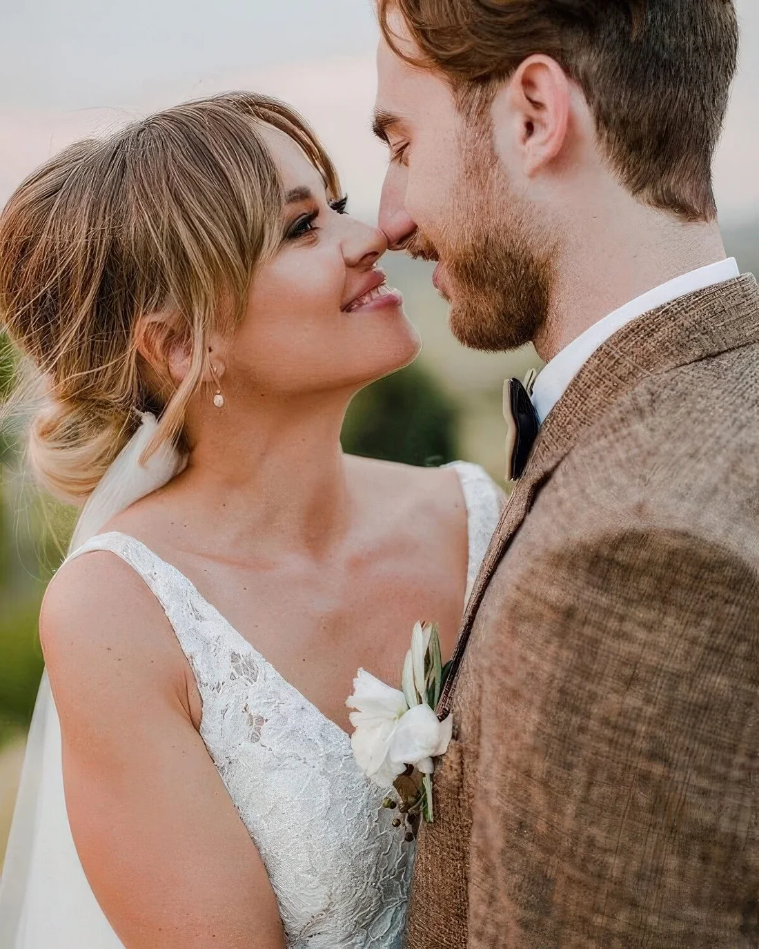 Low bun with a bump on top and layered bangs plus a veil are a chic and cool combo for a bridal look.