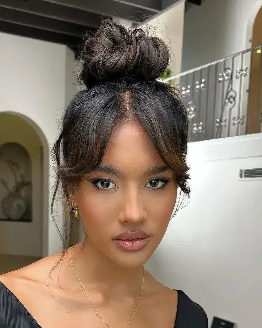 Quick and messy top knot with bangs and some hair down.