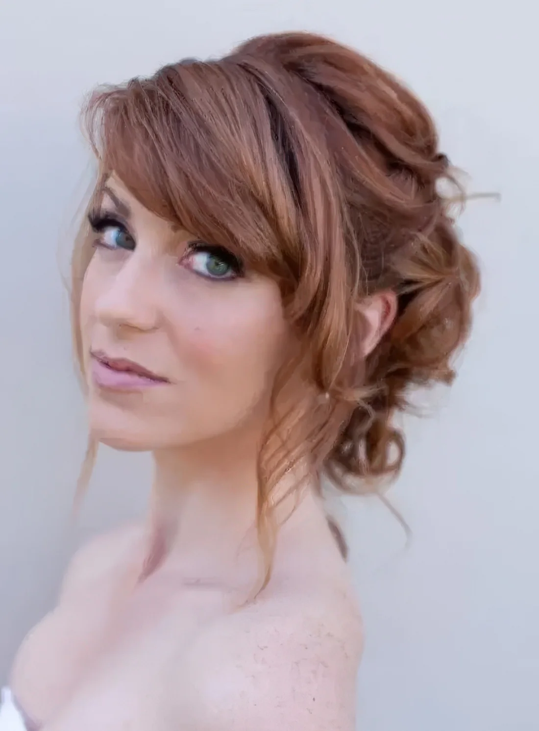 Romantic wavy updo with a bump and side bangs.