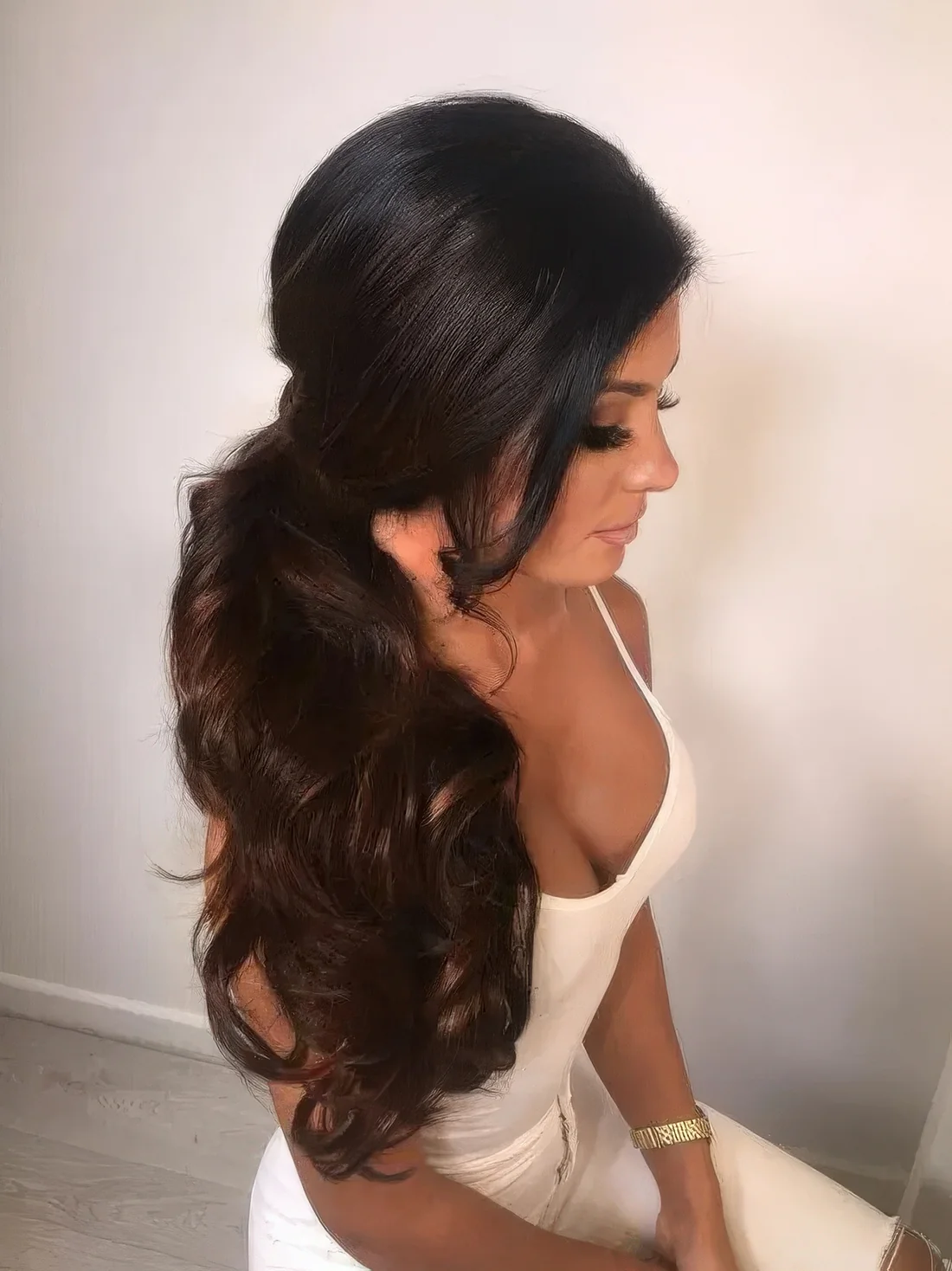 Dimensional wavy side poyntail with a sleek volume on top.