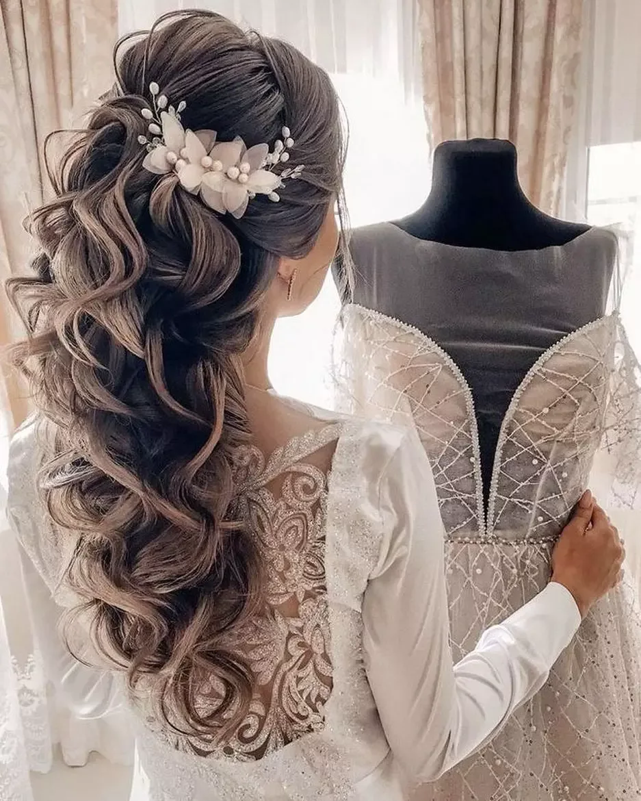chest wavy brunette ponytail shown as a wedding hairstyles ideas for long hair idea, featuring brunette color, shown in high bridal ponytail with floral accent