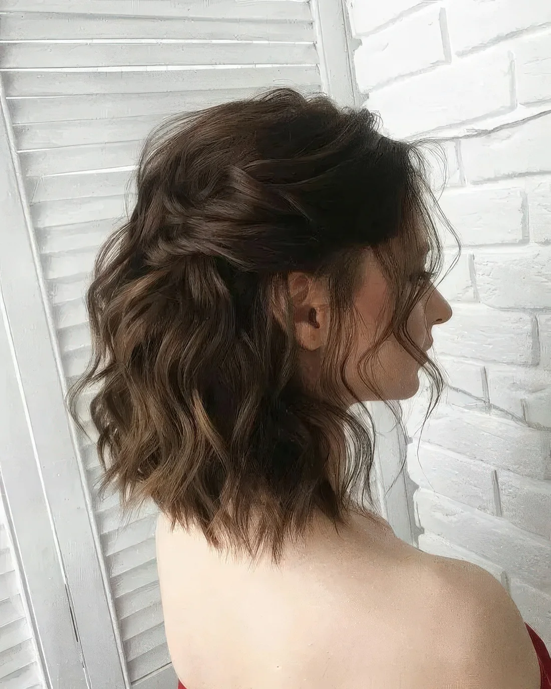 Dark brown medium-length wavy half-up hairstyle with a wavy top, locks framing the face and waves down.