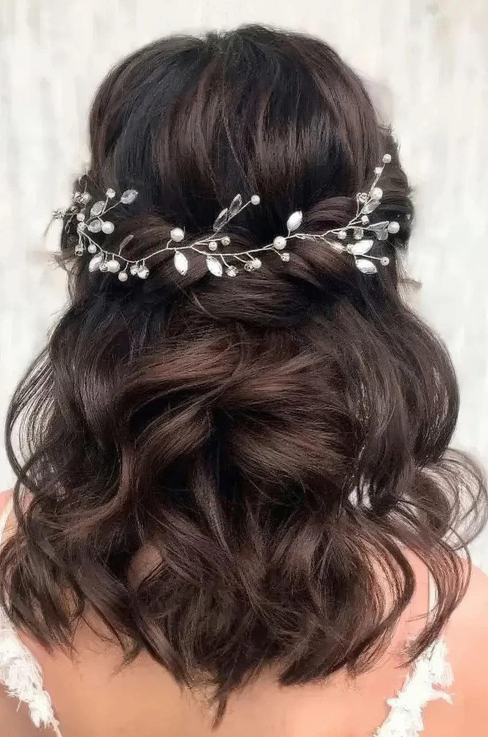 Charming twisted and wavy half updo with a volume on top accented with a pearl and rhinestone hair vine.