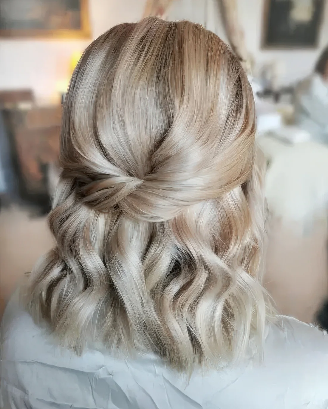 Chic blonde half updo with a twisted element, a bump and waves down.