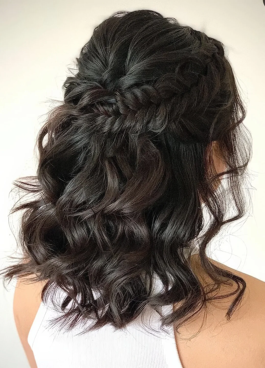 Half updo with a bump on top and a large braided halo plus curls down.