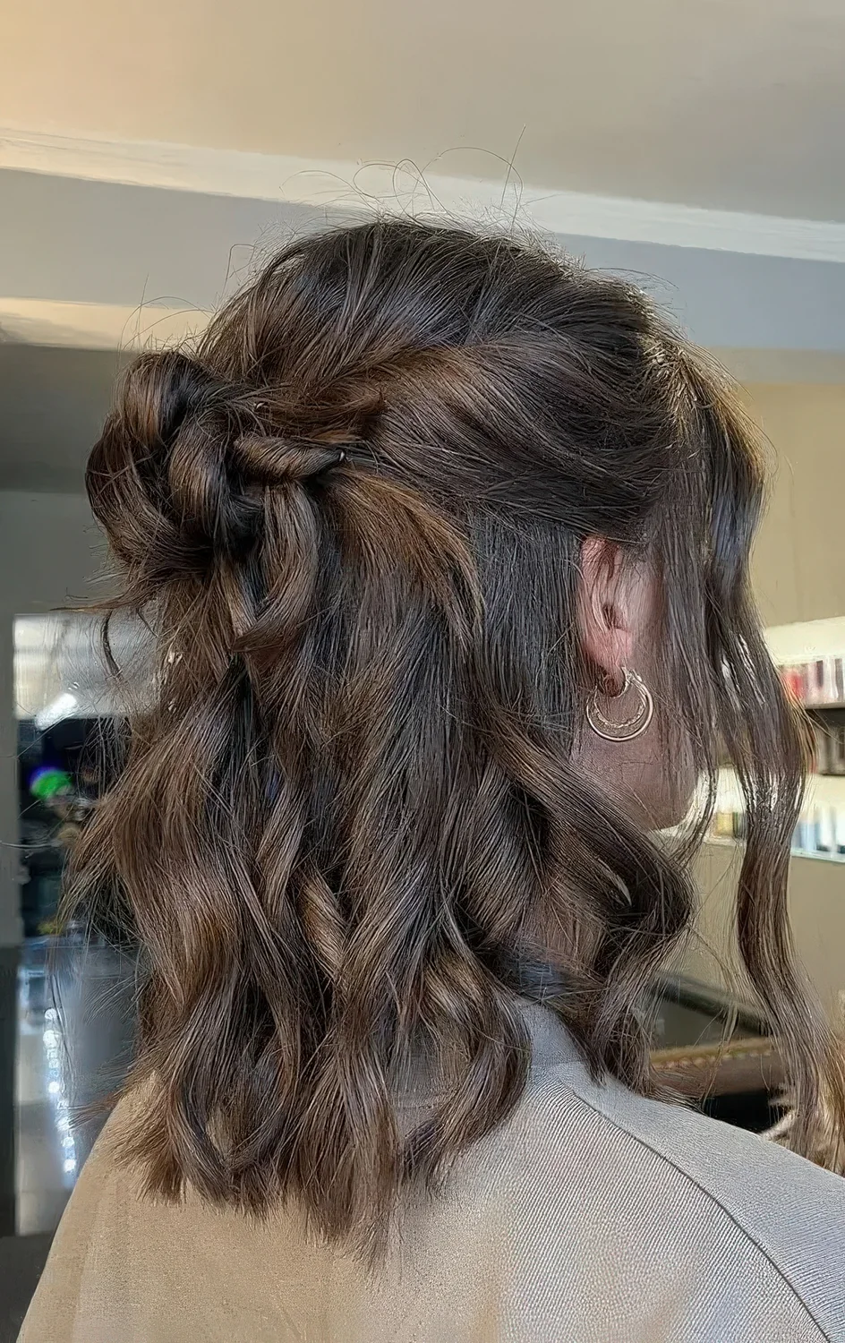 Half updo with a halo, a messy top knot and waves down plus locks framing the face.