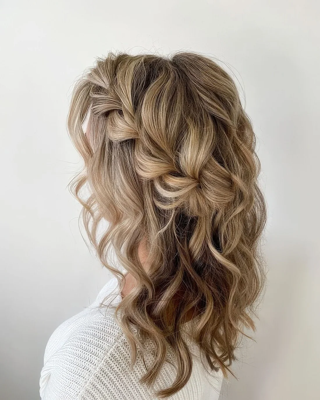 Girlish half updo with a loose side braid, waves and a bump on top.