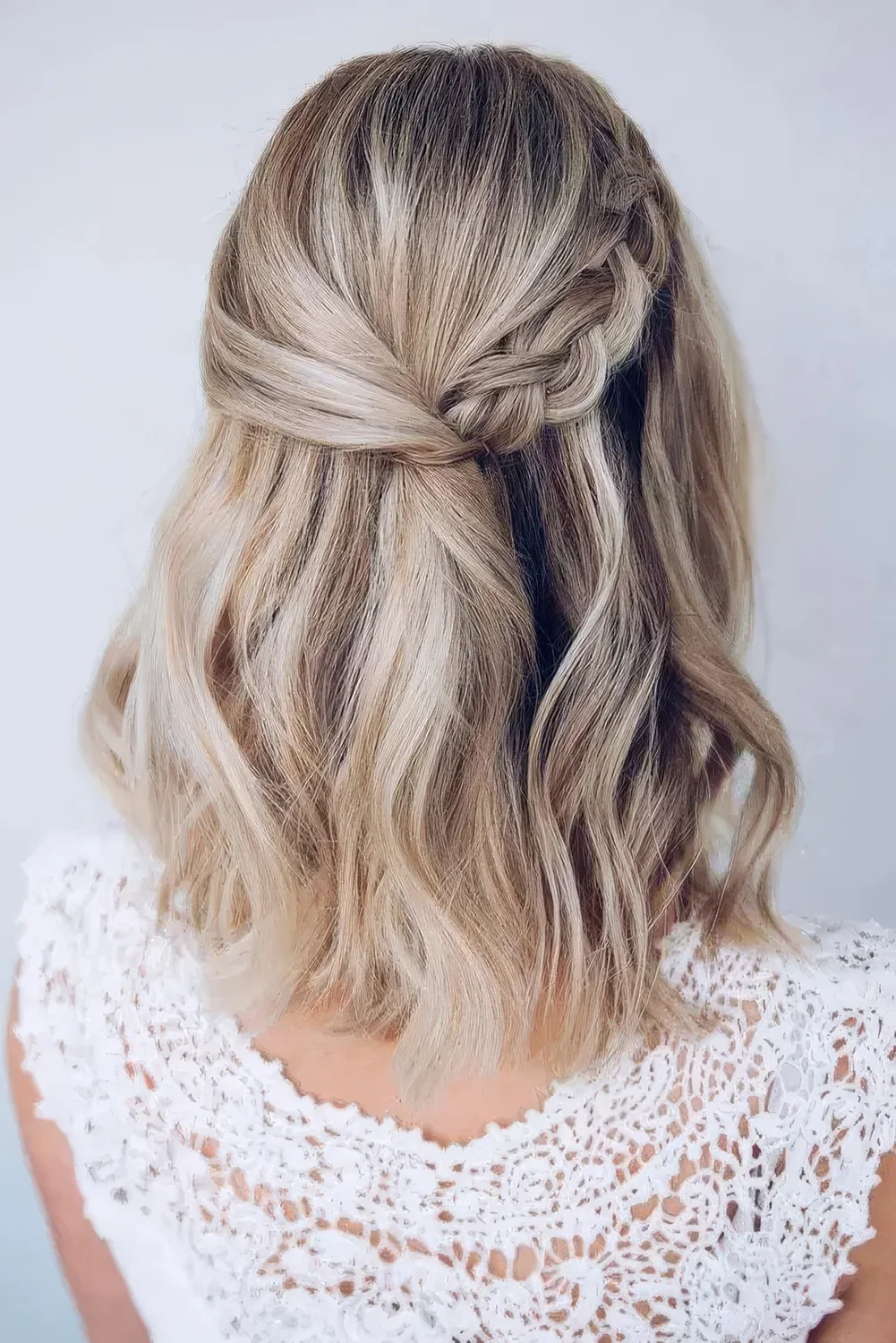 Blonde medium-length half updo with a side braid and waves down.