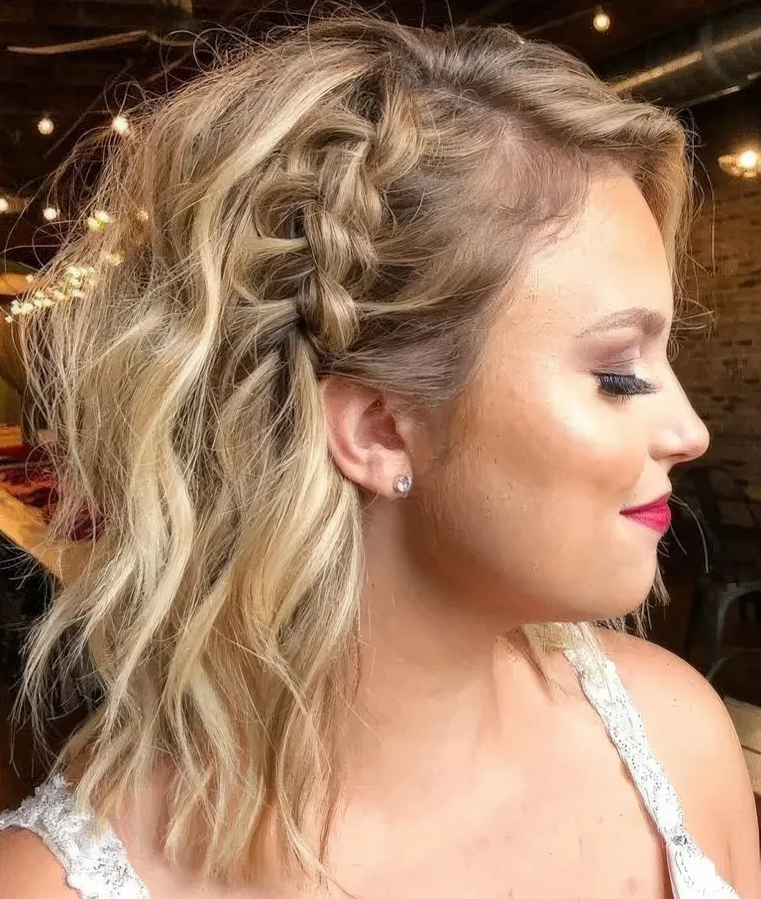 Creative blonde half updo with a large side braid and textural waves.