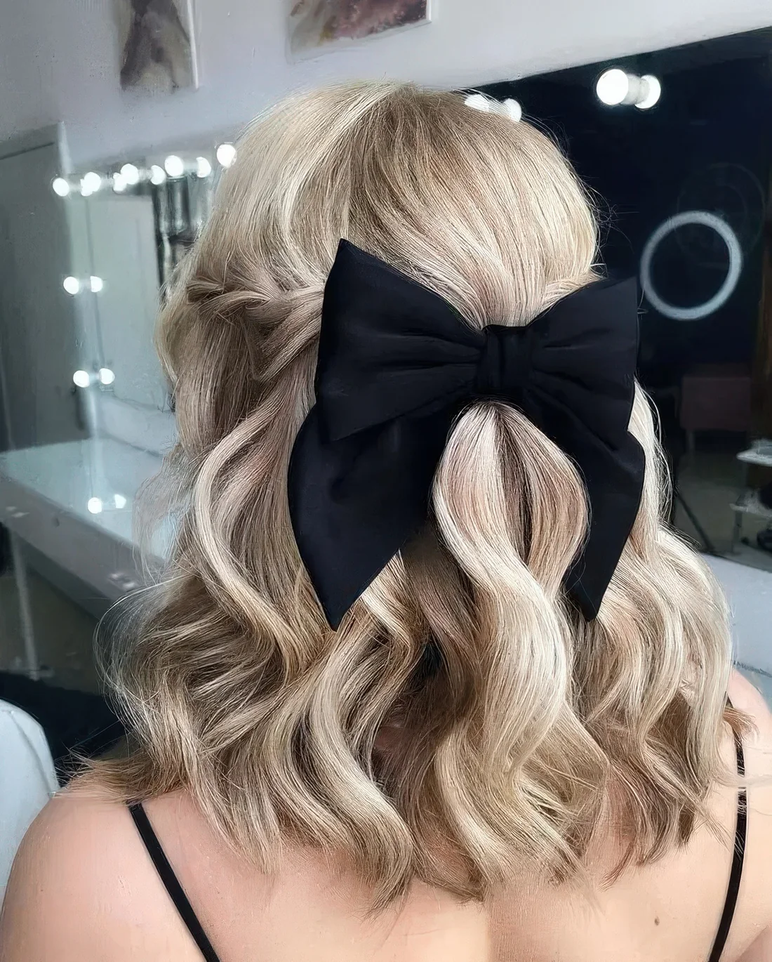 Glam and pretty half updo with twists, waves and a black bow.