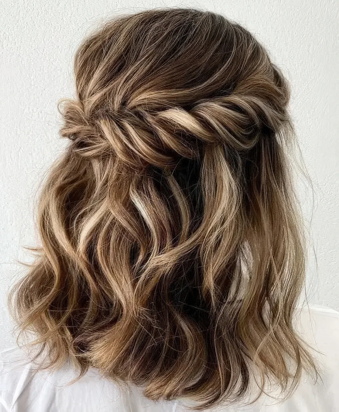 Wavy half updo with a bump on top,a twisted looped halo and waves down.