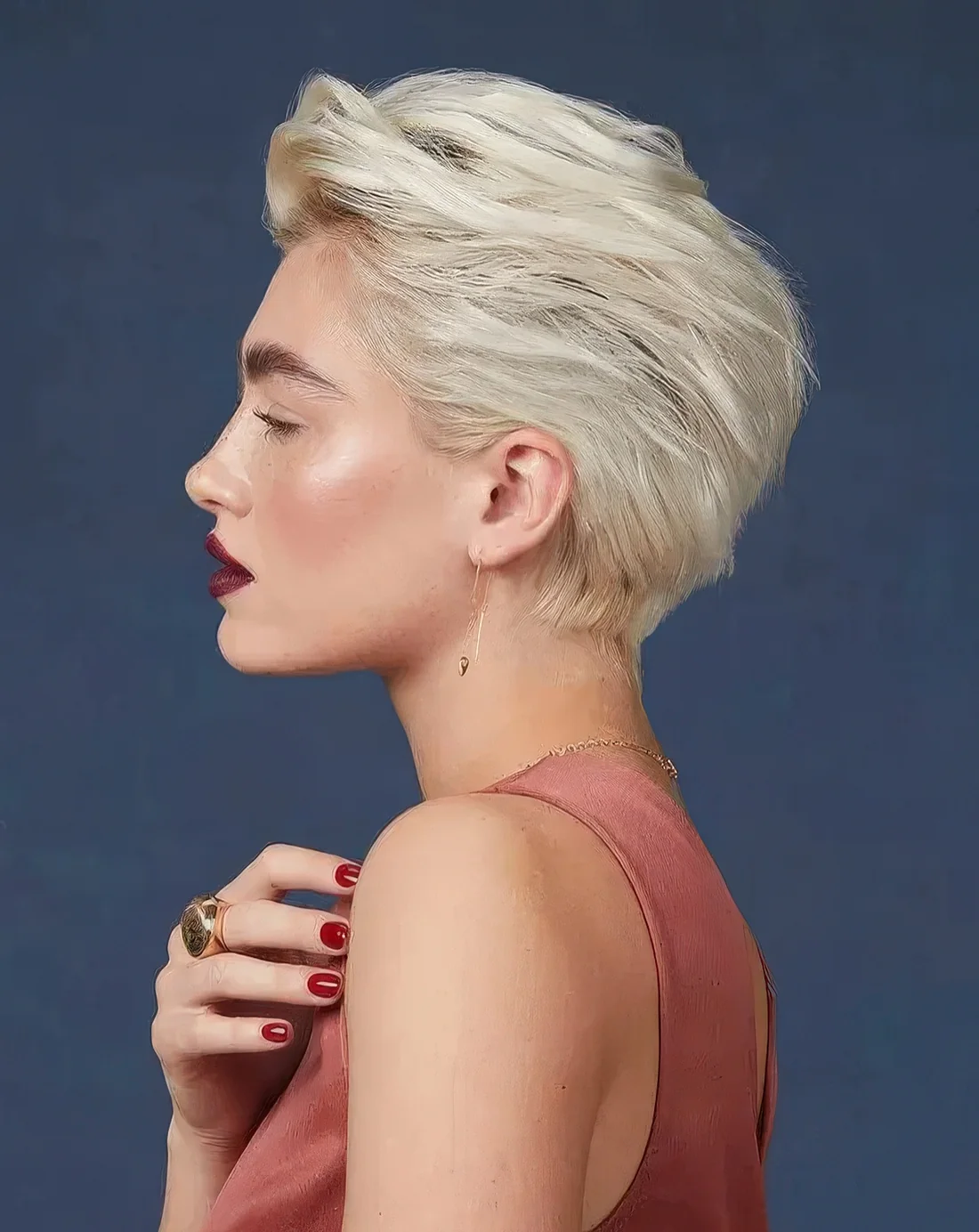 Blonde long pixie haircut with a lot of dimension and texture and a darker root.