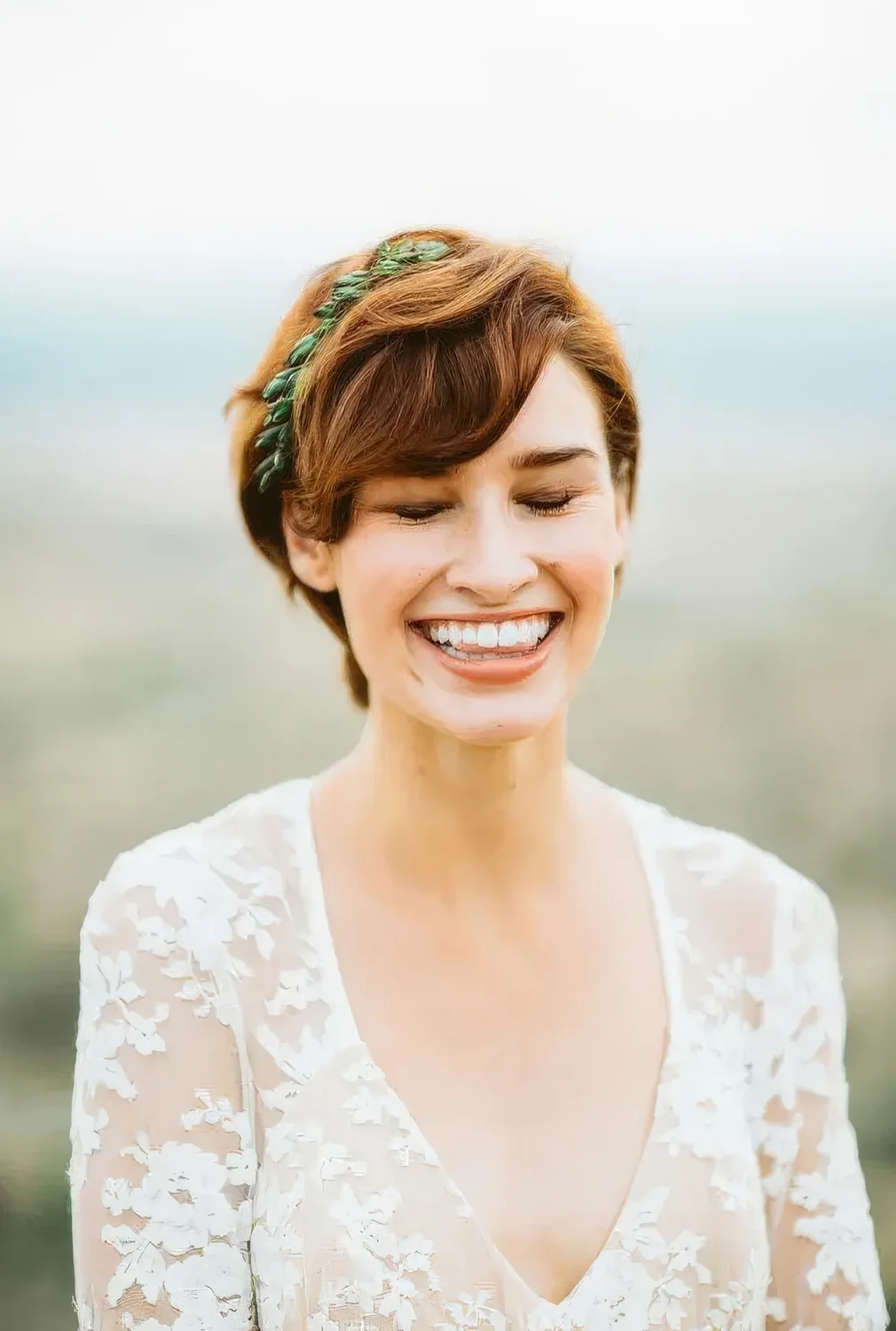 Ginger brown long pixie haircut with waves and a greenery touch.