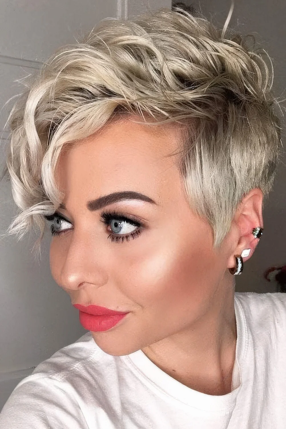 Long blonde pixie cut styled with waves.