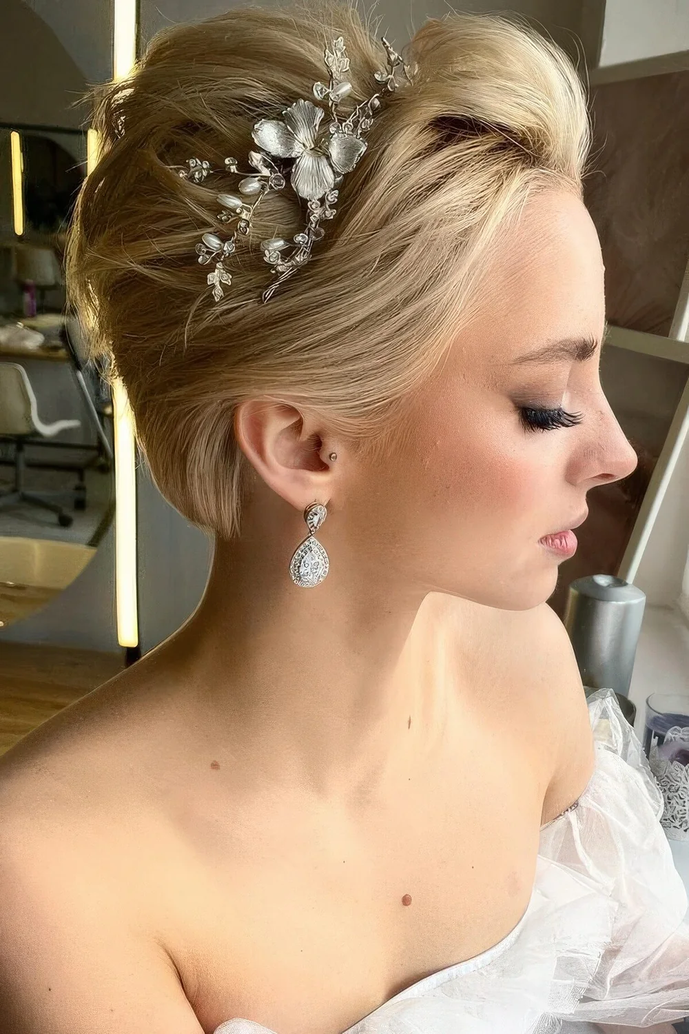 Long blonde pixie styled back and adorned with a pearl and flower hair vine.