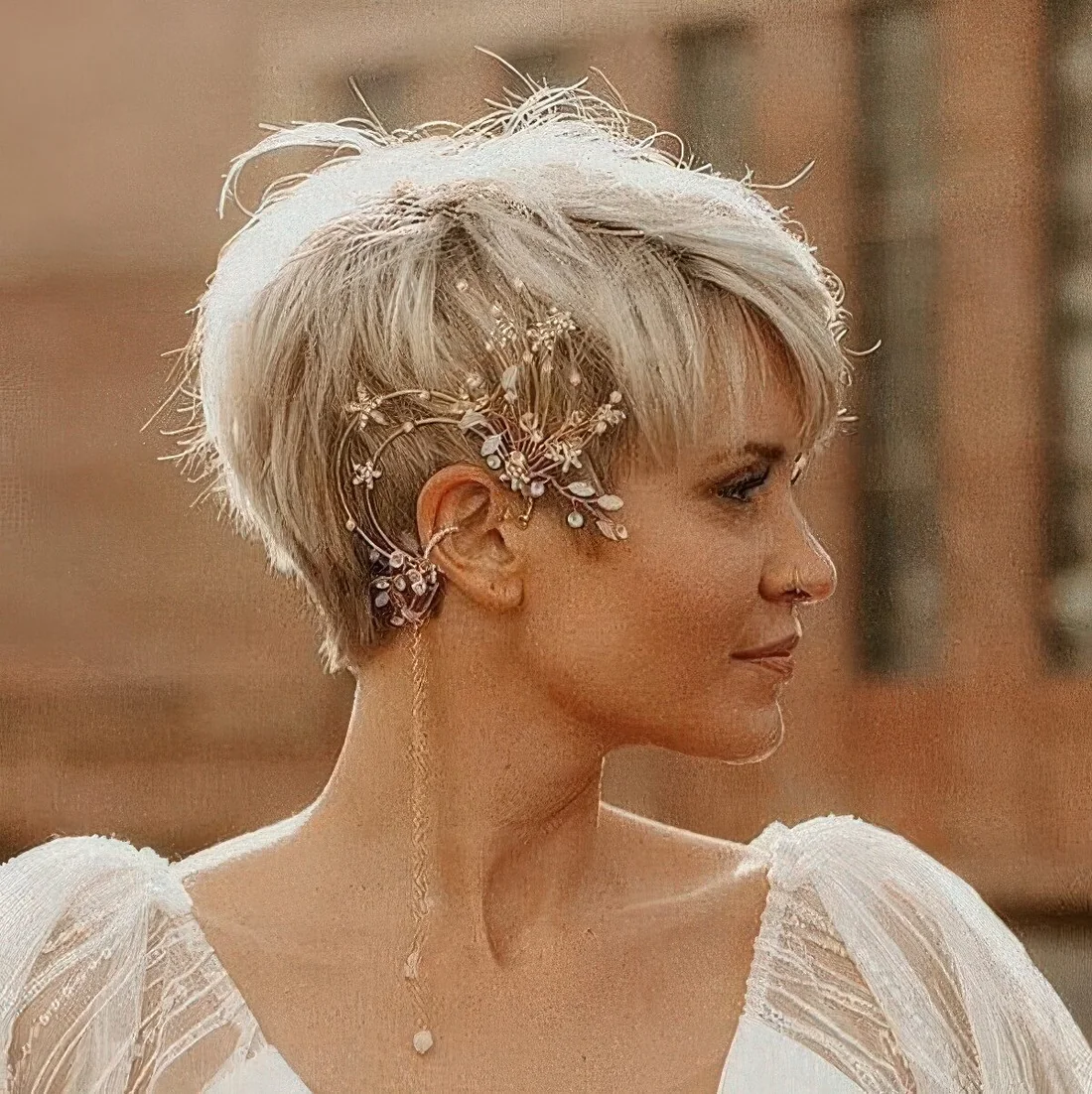 Long blonde pixie with bangs and a unique ear cuff with blooming coming on the hair and hanging down.