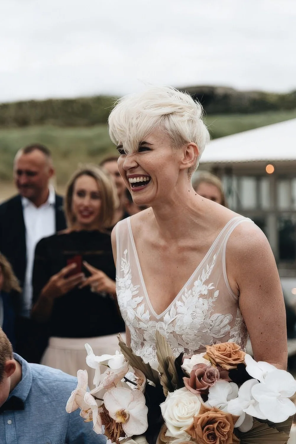 Long platinum blonde pixie haircut with bangs and a lot of volume.