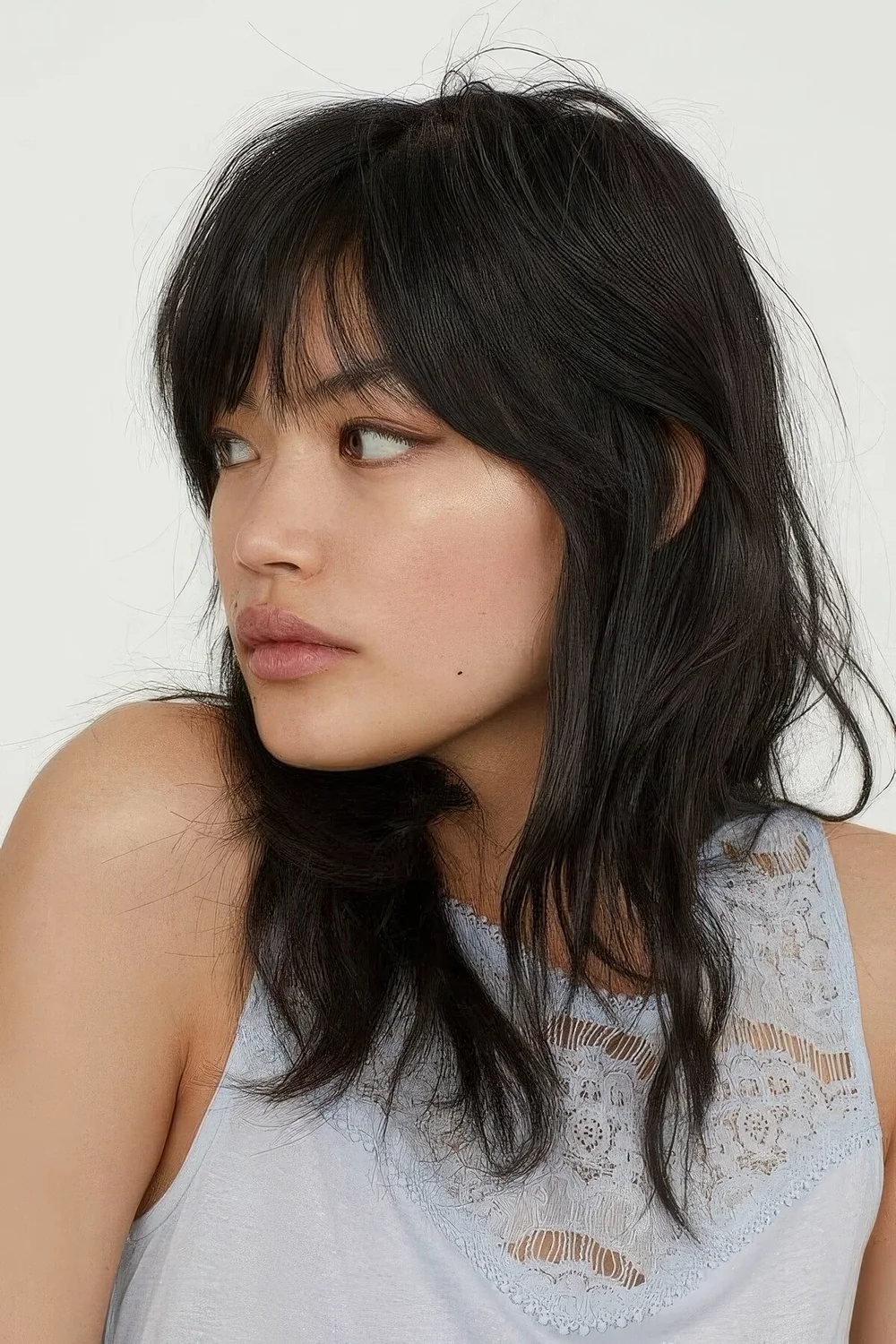 Black medium wolf cut with wispy bangs and waves down.