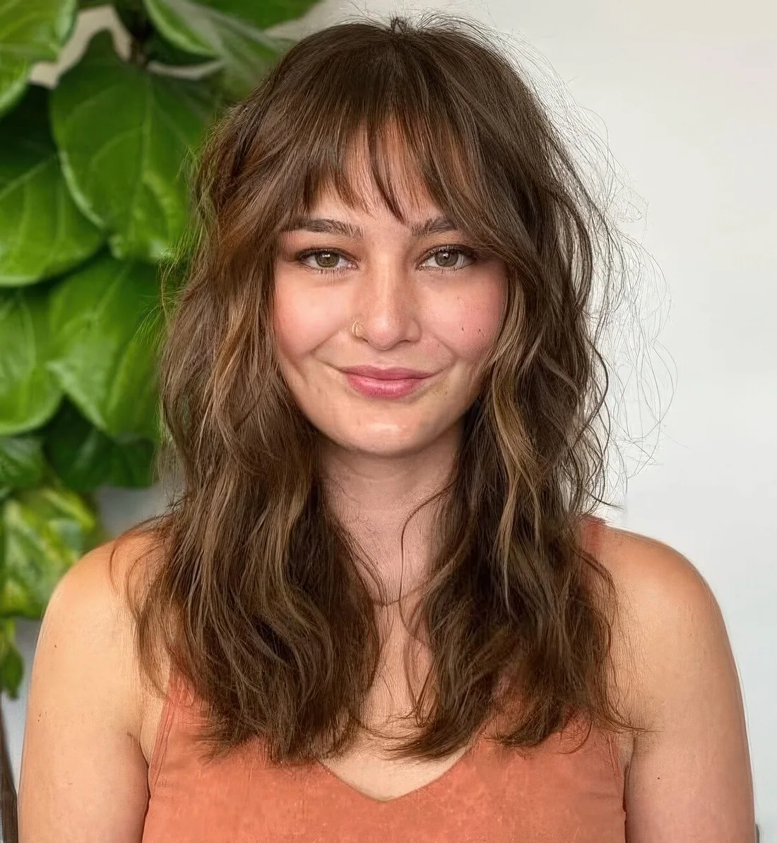 Brown long wolf haircut with wispy bangs, caramel balayage and soft waves to make the cut look cuter.