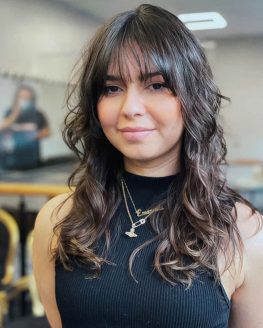 Dark brown long wolf haircut with wispy bangs and curls down that soften the look and make it girlish.