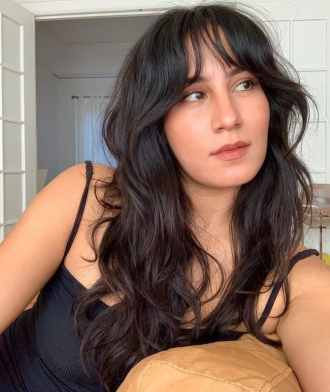 Dark brown wolf cut with waves and wispy bangs.
