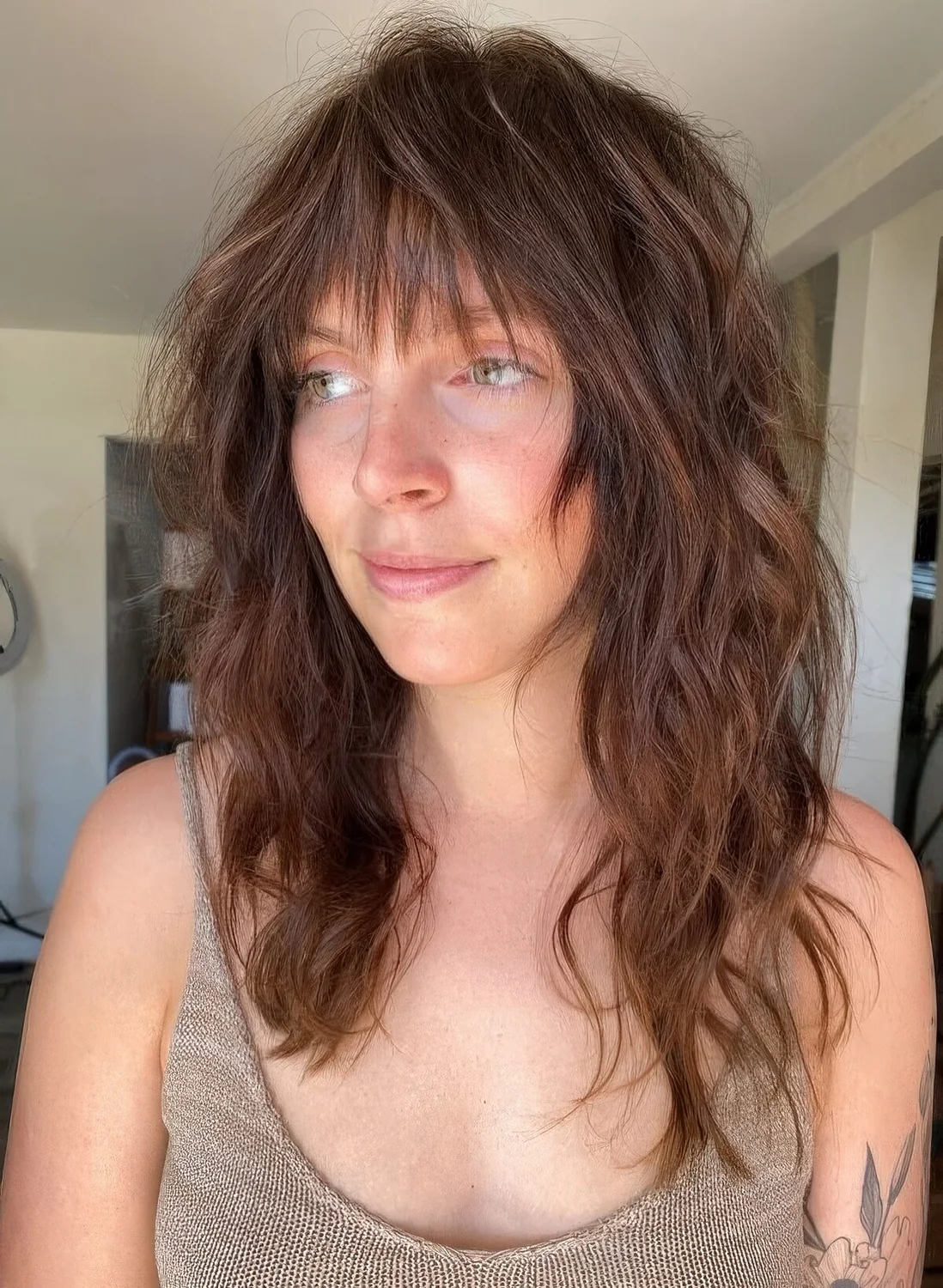 Dark brunette long wolf cut with wispy bangs and messy waves.