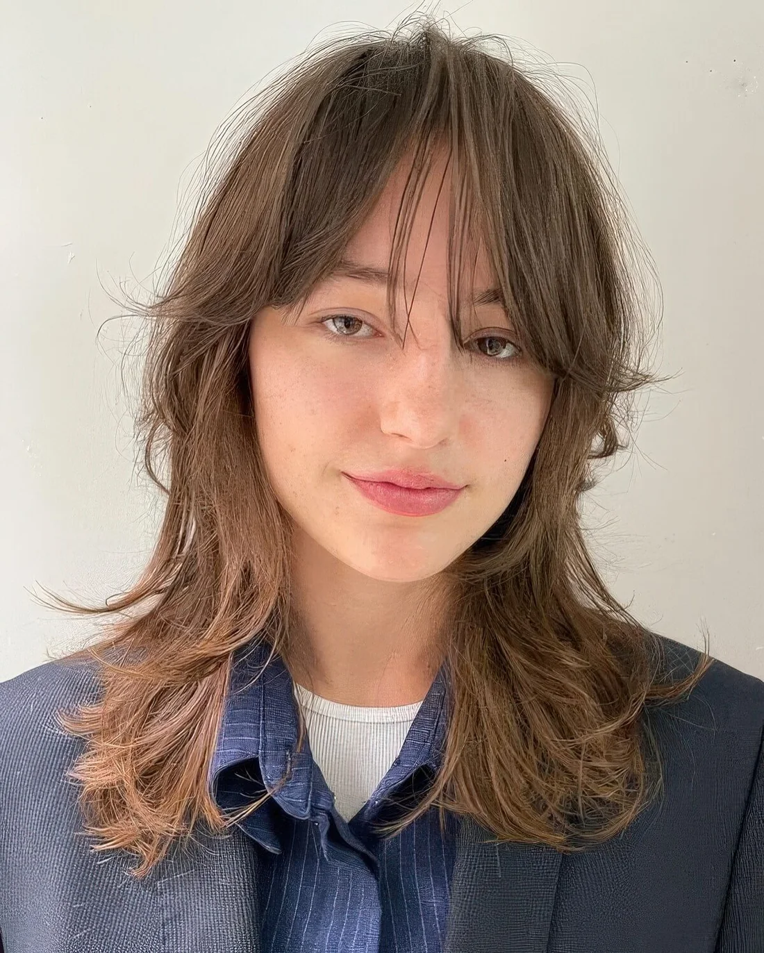 Light brunette medium wolf cut with wispy bangs and curled ends for that effortless 70s look.