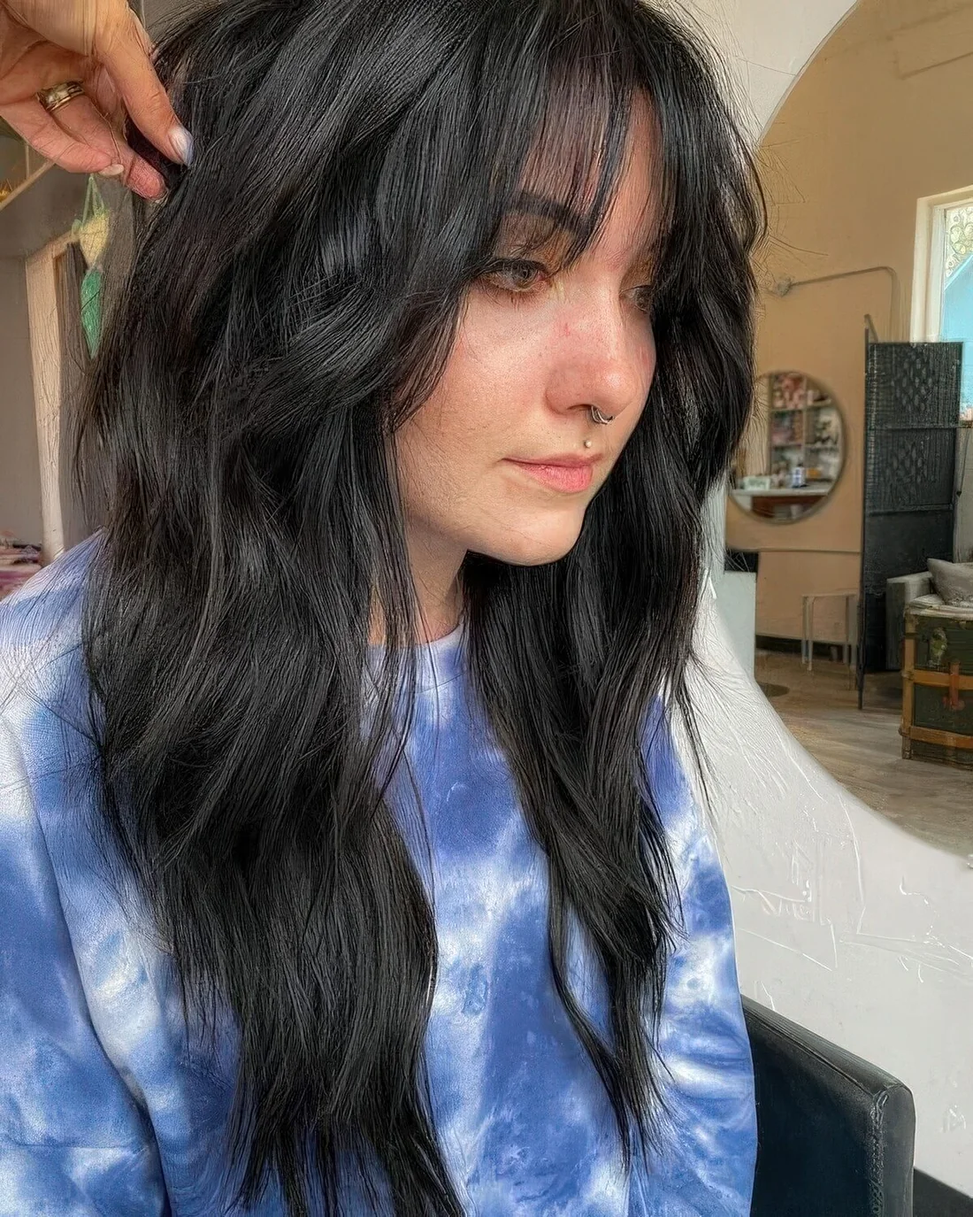Long black wolf haircut with wispy bangs and messy waves.