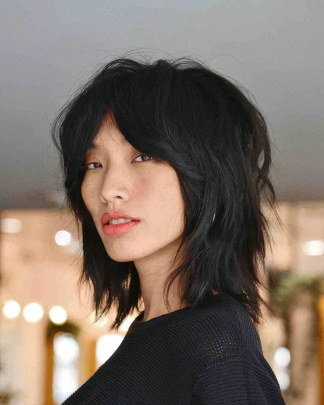 Black wolf cut with bottleneck bangs and layers, with center part.