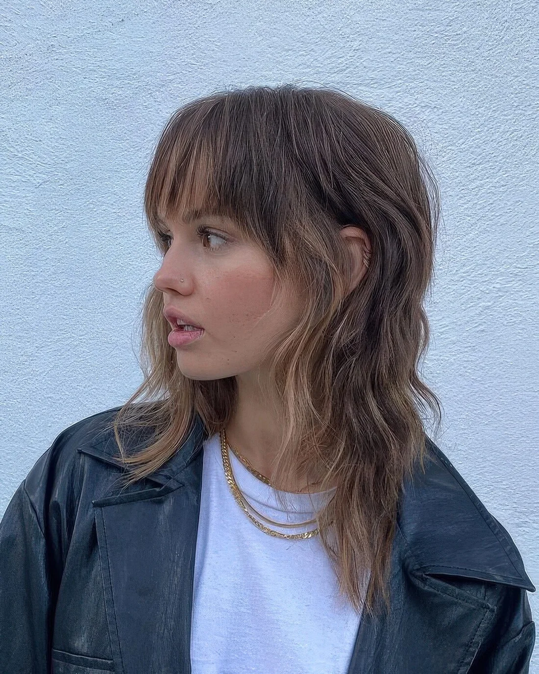 Chic brown wolf cut with caramel highlights, long bangs and layers.