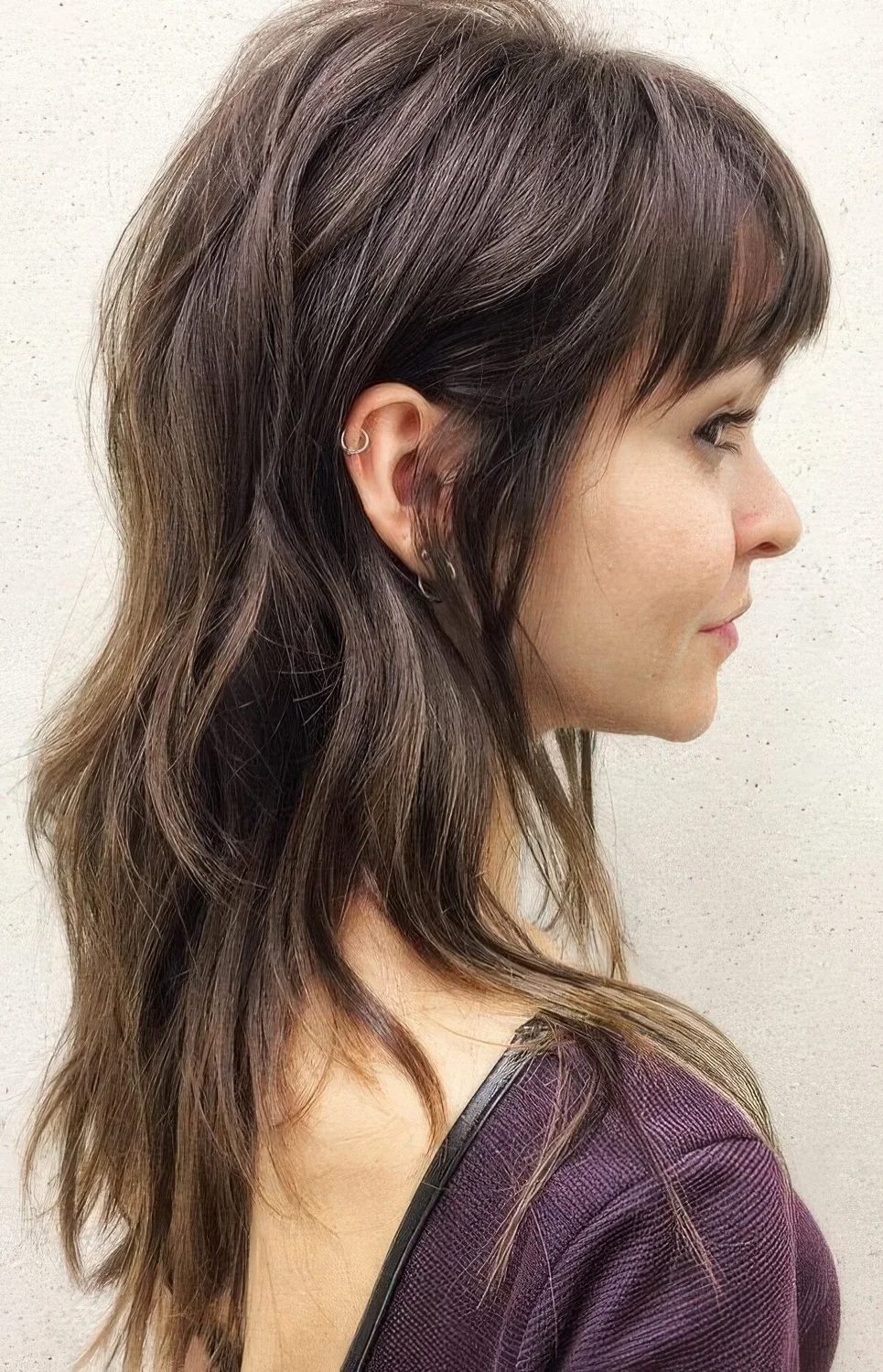 Dark brown wolf cut with bangs, long layers.
