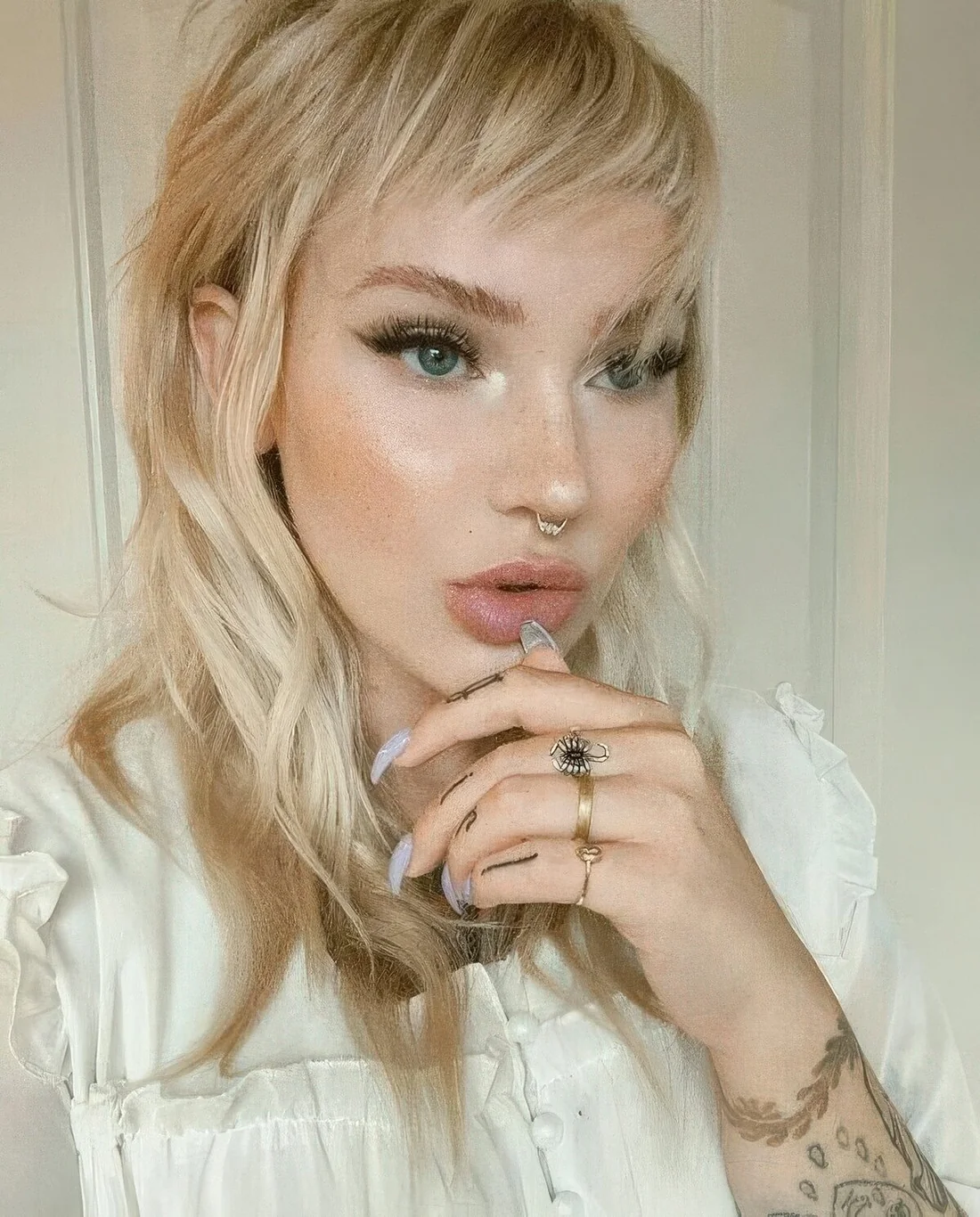 Long blonde wolf haircut with asymmetrical fringe and waves.