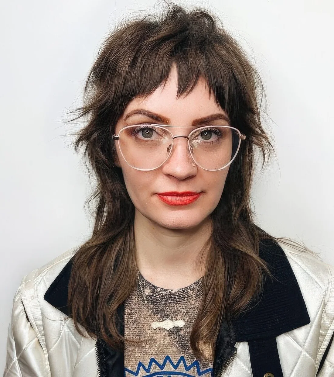 Long brown wolf cut with bottleneck bangs and layers.
