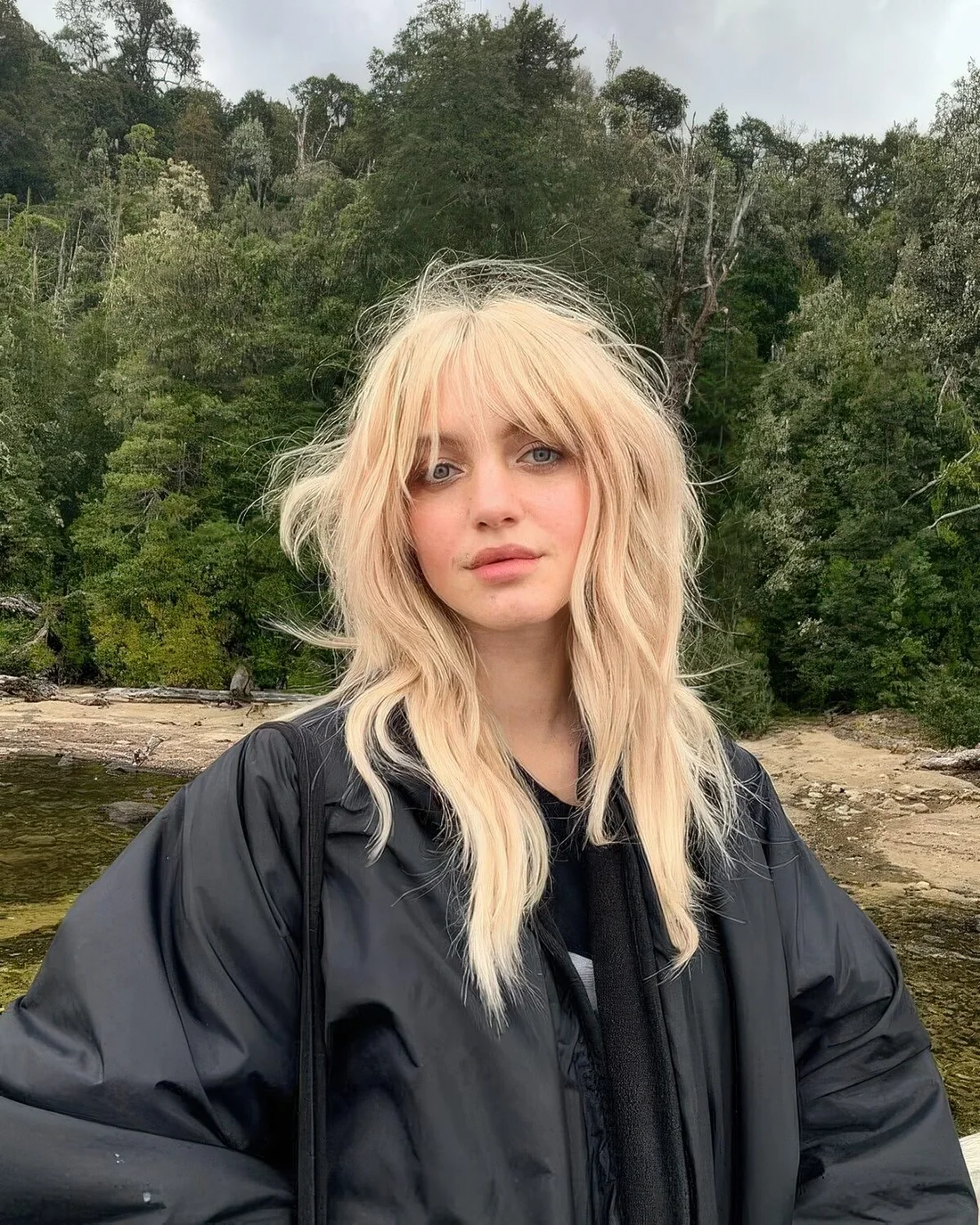 Shaggy long wolf cut done in a warm shade of blonde, with outgrown and bottleneck bangs, with long layers.